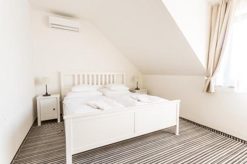 a white bedroom with a white bed and a window at Penzion Platan in Ňárad
