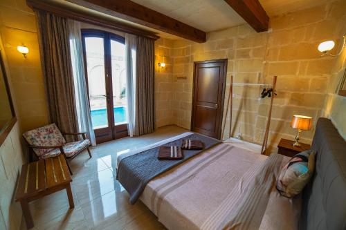 a bedroom with a large bed and a window at Sant Anton tal-Qabbieza Farmhouse in Kerċem