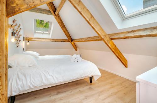 a bedroom with wooden ceilings and a white bed at Ardn-bnb Eglise in La-Roche-en-Ardenne