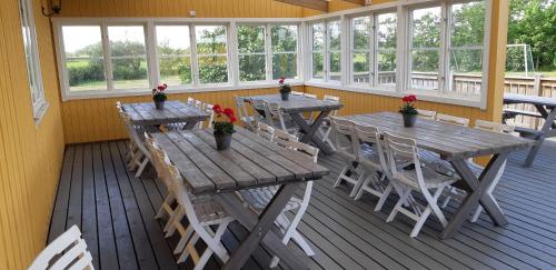 a porch with tables and chairs and windows at Björkängs Vandrarhem in Tvååker