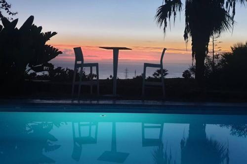 zachód słońca nad basenem z krzesłami i stołem w obiekcie Exclusive Villa Golf Private Pool w Adeje