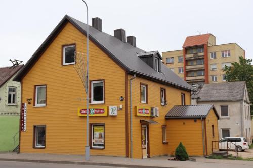 a large yellow building on the side of a street at Nakvynė apgyvendinimo paslaugos DAIVOS NAKVYNĖS NAMAI in Biržai