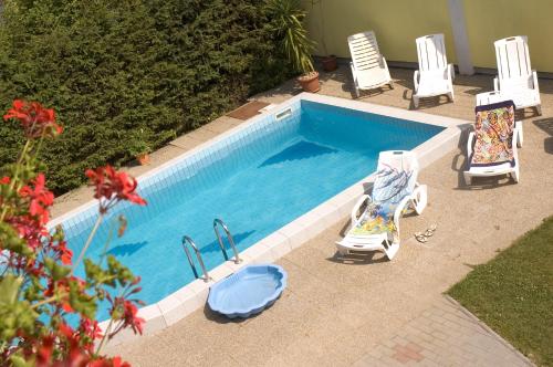 einen Pool mit zwei Gartenstühlen und einem Pool in der Unterkunft Erika Appartementhaus in Keszthely