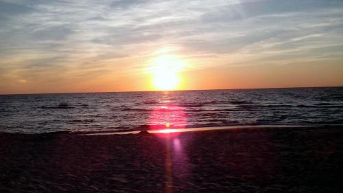 a sunset on the beach with the sun setting at Butas Nida Ramybė in Nida