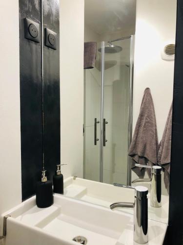 une salle de bain avec un lavabo blanc et un miroir dans l'établissement Room appart, à Narbonne