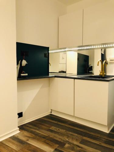 une cuisine avec des armoires blanches et un comptoir dans l'établissement Room appart, à Narbonne