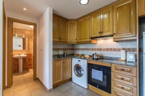 a kitchen with wooden cabinets and a washer and dryer at APARTAMENTOS SERRELLA - Rural Guadalest in Benimantell