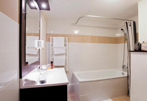 La salle de bains est pourvue d'un lavabo, d'une baignoire et d'une douche. dans l'établissement Aparthotel Adagio Access Marseille Saint Charles, à Marseille