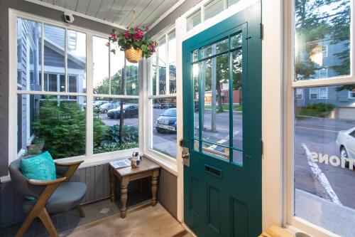 a green door on a porch with a chair and a table at Prince Street Suites in Charlottetown