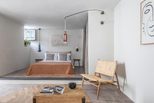 a bedroom with a bed and a chair and a table at SKIA-Cosy Living in Skiathos