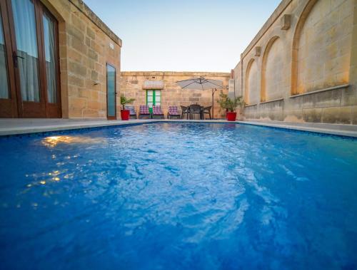 a large blue swimming pool in a building at Sant Anton tal-Qabbieza Farmhouse in Kerċem