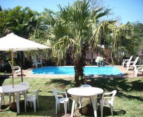 duas mesas e cadeiras ao lado de uma piscina em El Guembe Hostel House em Puerto Iguazú