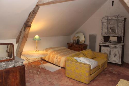 a bedroom with a bed and a couch and a table at A la Ferme de la Joie - Chambres d'Hôtes in Chevannes
