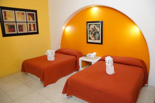 a hotel room with two beds with orange walls at Hotel Alikar in Santa Cruz Huatulco