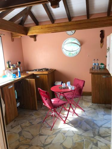 a kitchen with red chairs and a table in a room at Le studio de Véro in Sainte-Anne