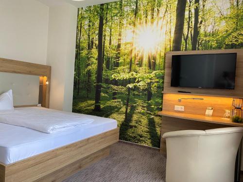 a bedroom with a tv and a mural of a forest at Weinhotel Römerbad in Bad Salzuflen