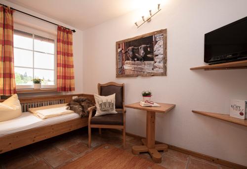 a room with a bed and a chair and a tv at Hotel-Gasthof Der Wiesengrund in Bad Hindelang