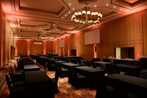 una sala de conferencias con mesas, sillas y una pantalla en Alejandro 1º Hotel en Salta