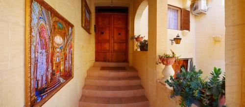 a hallway with a wooden door and stairs with plants at Narcisa Farmhouse B&B in Nadur