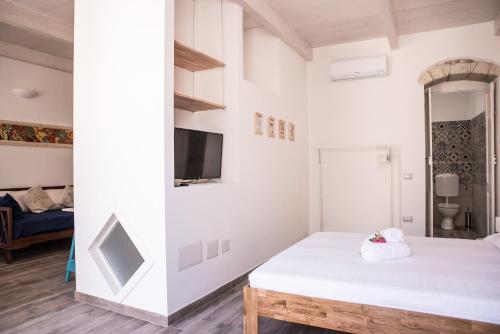 a room with a bed and a tv and a couch at B&B LE TRE CHIOCCIOLE in SantʼAntìoco