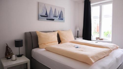 um quarto com uma cama com lençóis brancos e uma janela em Kapitainskoje direkt am Hafen Flensburgs em Flensburg