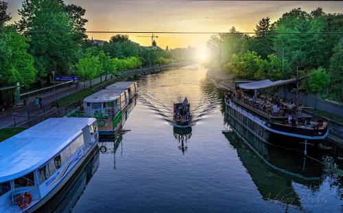 two boats are docked on a river at sunset at Take PRO Timisoara Apartment in Timişoara