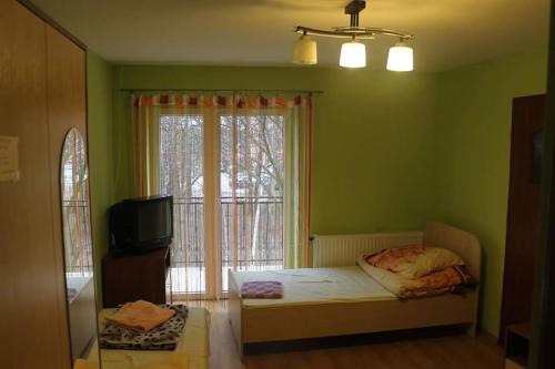 Dormitorio verde con cama y ventana en Bar Oaza, en Szczerców