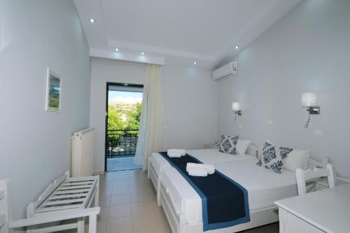 a white bedroom with a bed and a window at Ifestos Hotel in Mirina