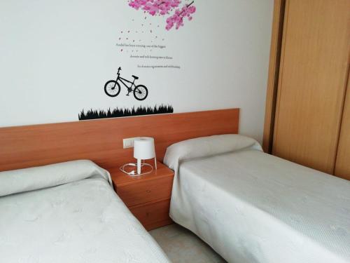 オ・グローベにあるApartamentos O Groveのベッドルーム1室(ベッド2台付)、壁に自転車1台が備わります。