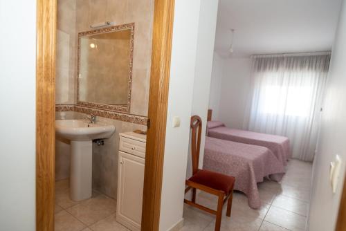 a small bathroom with a sink and a bed at Apartamentos O Grove in O Grove