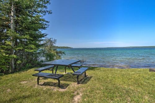 a picnic table and benches on the grass near the water at Pet-Friendly Charlevoix Cabin Walk to Lakefront! in Charlevoix
