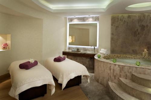 a bathroom with two beds and a bath tub at Millennium Al Rawdah Hotel in Abu Dhabi
