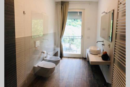een badkamer met 2 toiletten, een wastafel en een raam bij Wind Rose Apartments 2 in Nago-Torbole