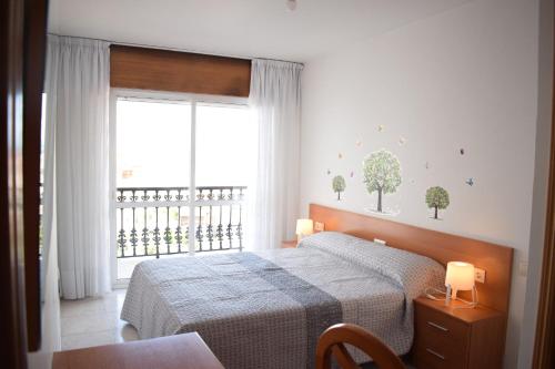a bedroom with a bed and a large window at Apartamentos O Grove in O Grove