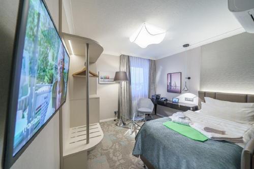 クックスハーフェンにあるStrandhotel Duhnenのベッド1台、薄型テレビが備わるホテルルームです。