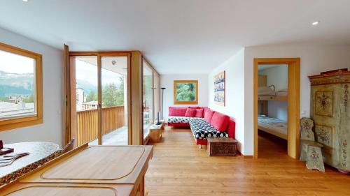 ein Wohnzimmer mit einem roten Sofa und einem Bett in der Unterkunft Chavriöl in Pontresina