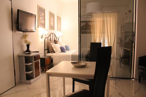 a room with a bed and a table and a television at La suite del centro storico in Matera
