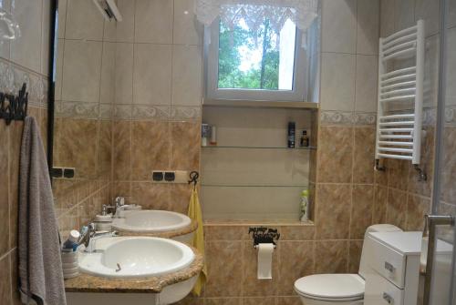 a bathroom with two sinks and a toilet and a window at SONIA in Polanica-Zdrój