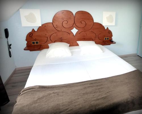 a bedroom with a large bed with a wooden headboard at Auberge de la Rivière in Foncine-le-Haut