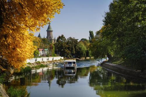 a boat on a river with a building in the background at Take PRO Timisoara Apartment in Timişoara