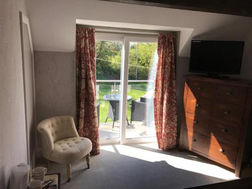 a living room with a chair and a sliding glass door at Bryn Goleu Bed & Breakfast in Llandudno