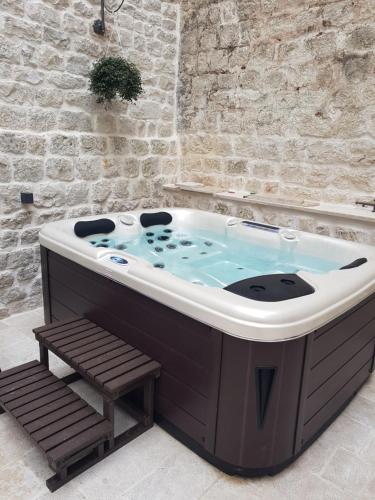 a jacuzzi tub with a bench in a room at Villa Kudelik - Stone Story in Trogir