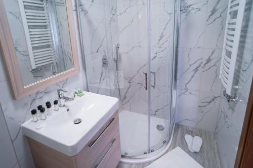a white bathroom with a shower and a sink at Apartamenty Liliowe SPA & Wellness in Murzasichle