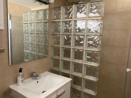 baño con lavabo y pared de cristal en Apartamentos SOL y PLAYA Torremolinos, en Torremolinos