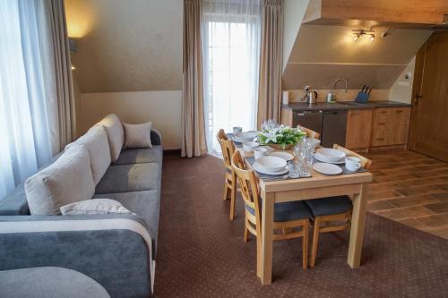 a living room with a couch and a table with chairs at Apartamenty Liliowe SPA & Wellness in Murzasichle