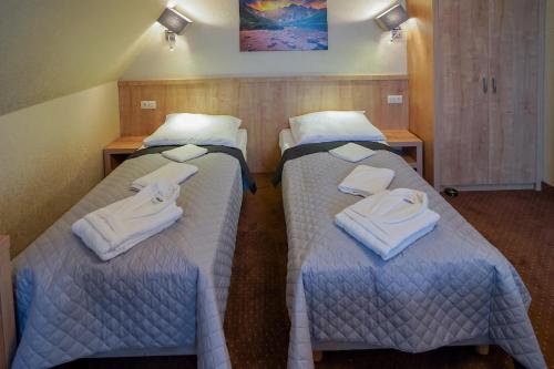 a hotel room with two beds with towels on them at Apartamenty Liliowe SPA & Wellness in Murzasichle