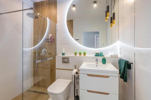 a bathroom with a sink and a toilet and a mirror at atHome Suites in Kraków