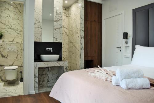 sypialnia z łóżkiem oraz łazienka z umywalką w obiekcie Antares Luxury Rooms w Splicie