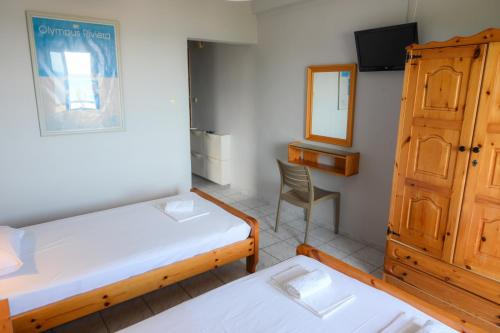 a room with two beds and a cabinet and a mirror at Giorgos Apartments Sea View in Olympiaki Akti