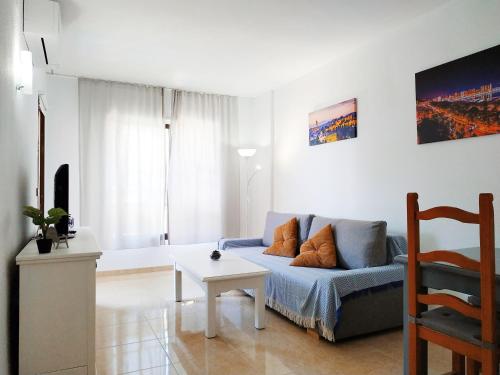 uma sala de estar com um sofá azul e uma mesa em Apartamento Ronda IV - Los Boliches em Fuengirola